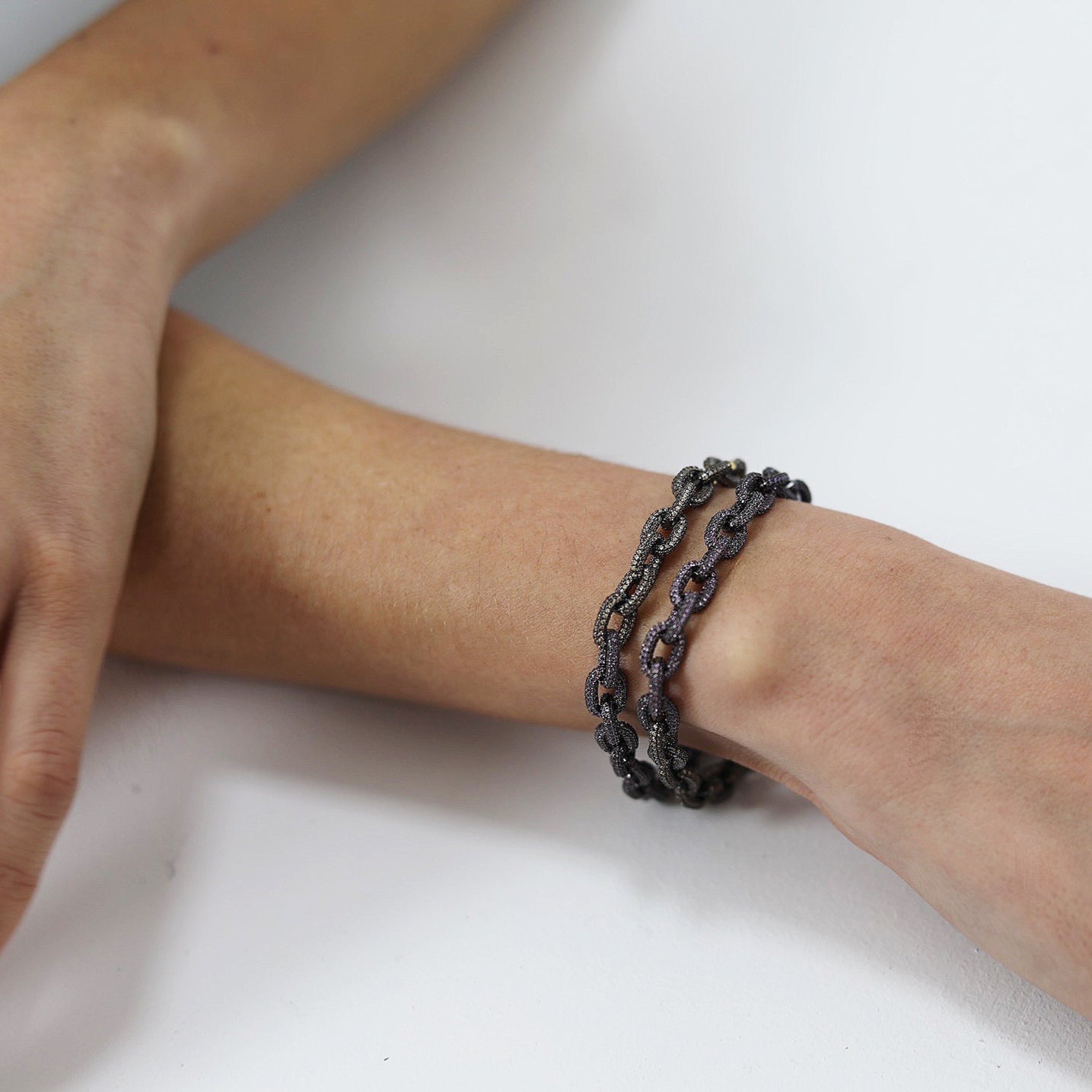 Pulsera realizada en plata de primera ley 925 milésimas, con dos acabados. Por un lado, los eslabones están finalizados con un baño de rodio negro, y están cubiertos por pequeñas piedras en talla circular en violeta, rosa y naranja. Por último, encontramos el cierre de la caja con seguridad acabado con un baño de oro amarillo.