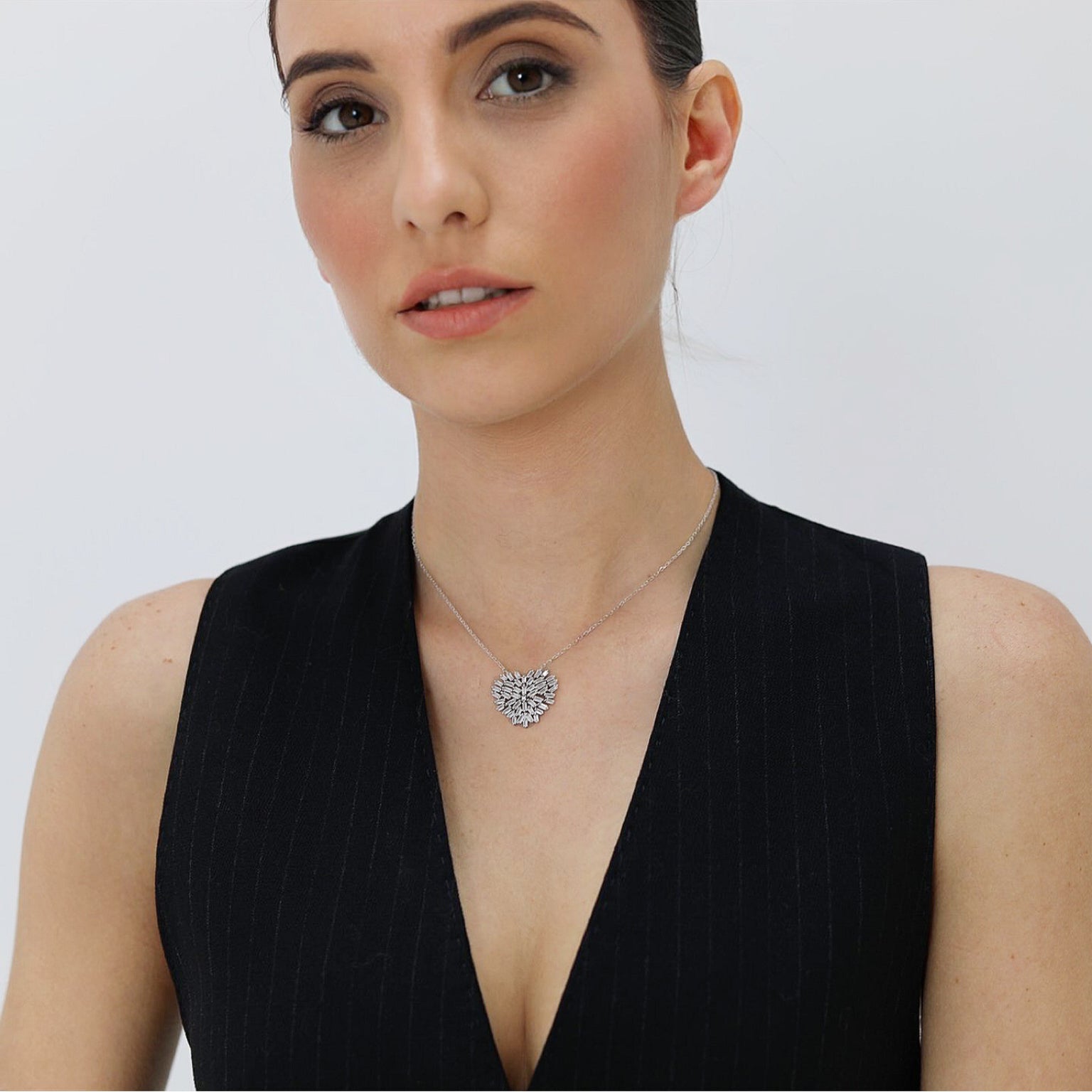 Realizado en plata de primera ley 925 milésimas, acabado con un baño de rodio blanco, su forma principal es un corazón formado por pequeñas piedras en talla baguette, sujetas por garras. Tiene una cadena de 36 centímetros más 6 adicionales ajustables.