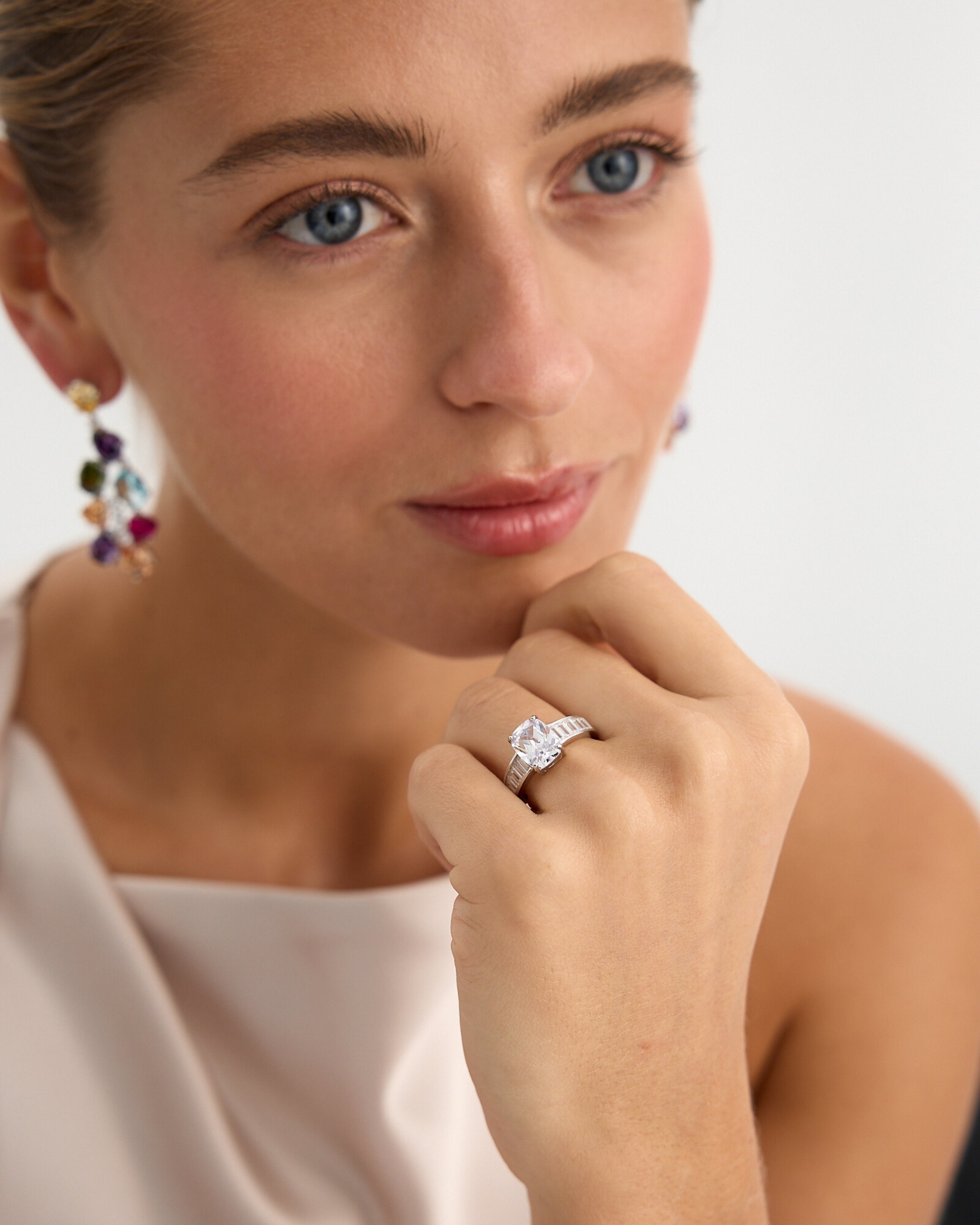 Anillo blanco elegante con piedra central en talla cojín y diseño contemporáneo femenino.