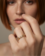 Anillo dorado con diseño de eslabones y pequeñas circonitas blancas, elegante y sofisticado.