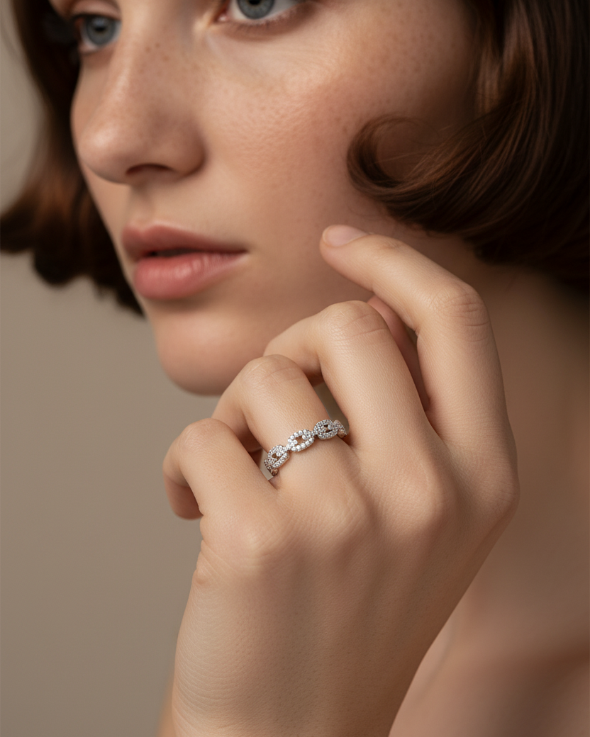 Anillo femenino de eslabones entrelazados con delicado brillo blanco.
