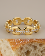 Anillo minimalista con eslabones y circonitas blancas que aportan un brillo sutil y elegante.