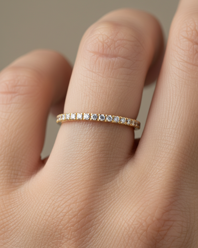Anillo tipo alianza con baño de oro amarillo de 18k y circonitas blancas en talla circular de 1 mm, diseño fino y elegante para uso diario.