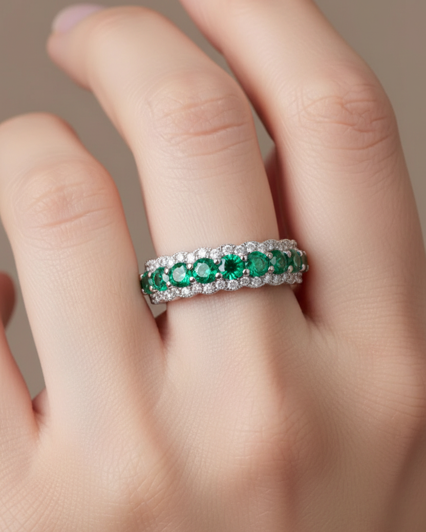 Anillo luminoso con piedras verdes esmeralda y circonitas blancas en un diseño delicado y femenino.