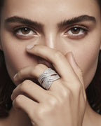 Detalle de anillo de plata 925 con pequeñas piedras blancas y diseño elegante cruzado.