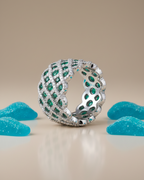 Detalles del anillo STILL con contraste luminoso de piedras blancas y verdes esmeralda.