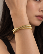 Brazalete dorado VITA con textura lineal y diseño rígido de gran presencia visual.
