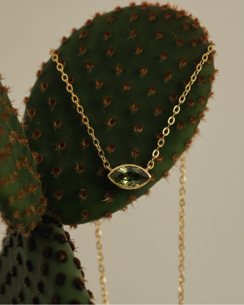 Collar elegante con piedra verde en talla marquesa y acabado en oro amarillo de 18 kt, diseño fino y femenino.