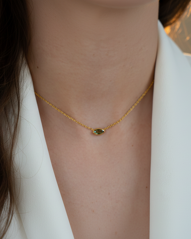 Collar con piedra verde en talla marquesa y acabado en oro amarillo de 18 kt, estilo sutil y sofisticado.
