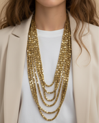Collar joya PEDRI con siete cadenas doradas en capas y diseño de carácter marcado.
