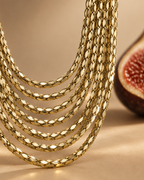 Collar PEDRI multicapa con acabado dorado y siete tiras de cadena superpuestas.