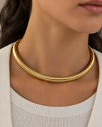 Collar SERA tipo gargantilla tubular con acabado dorado y cierre posterior.