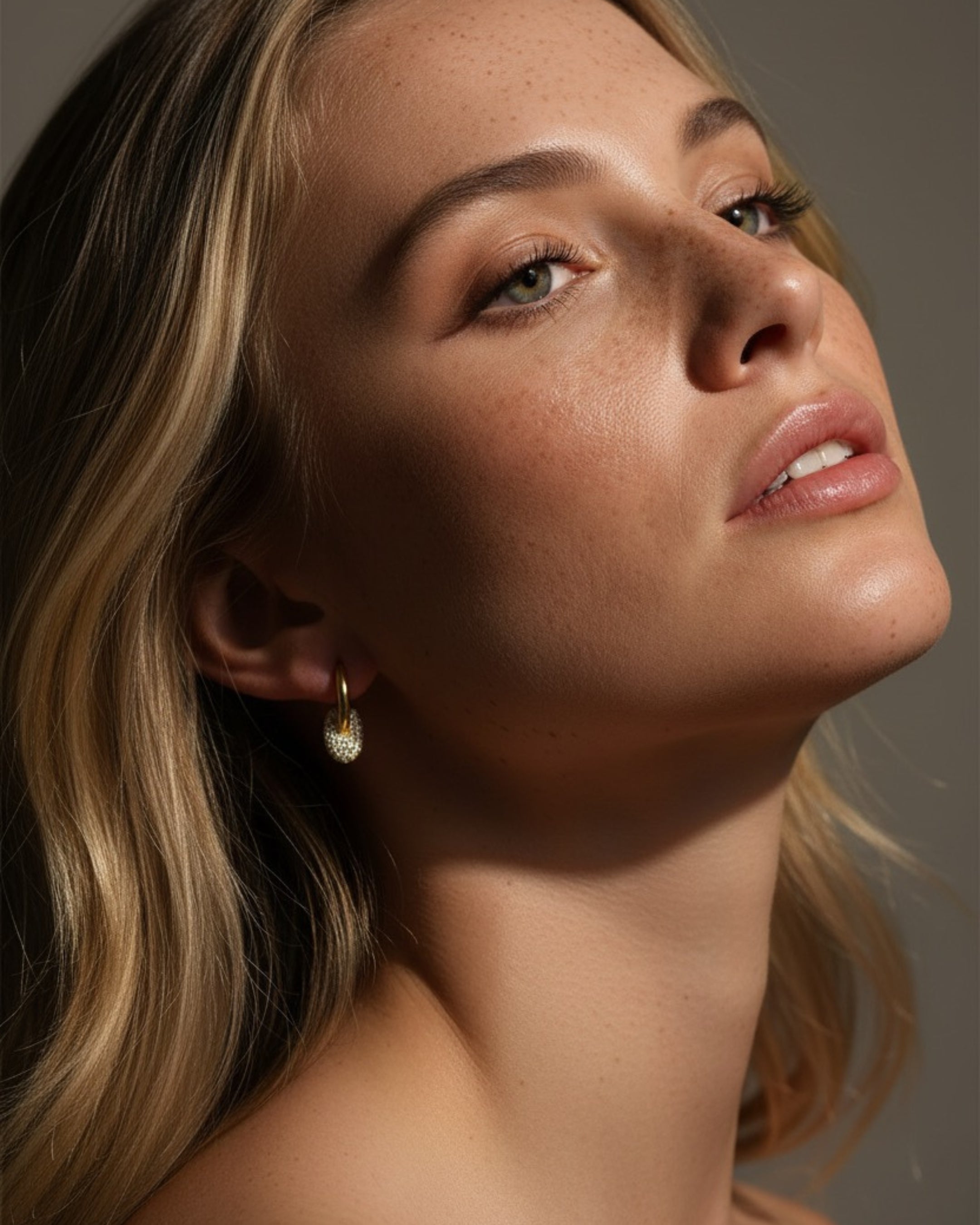 Detalle de pendientes con piedras blancas en talla circular que aportan brillo sutil al diseño.