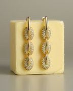 Pendientes dorados con piedras brillantes y diseño femenino y contemporáneo.
