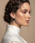 Primer plano de pendientes Epoc con piedra azul central y pequeñas piedras que aportan luz al diseño.