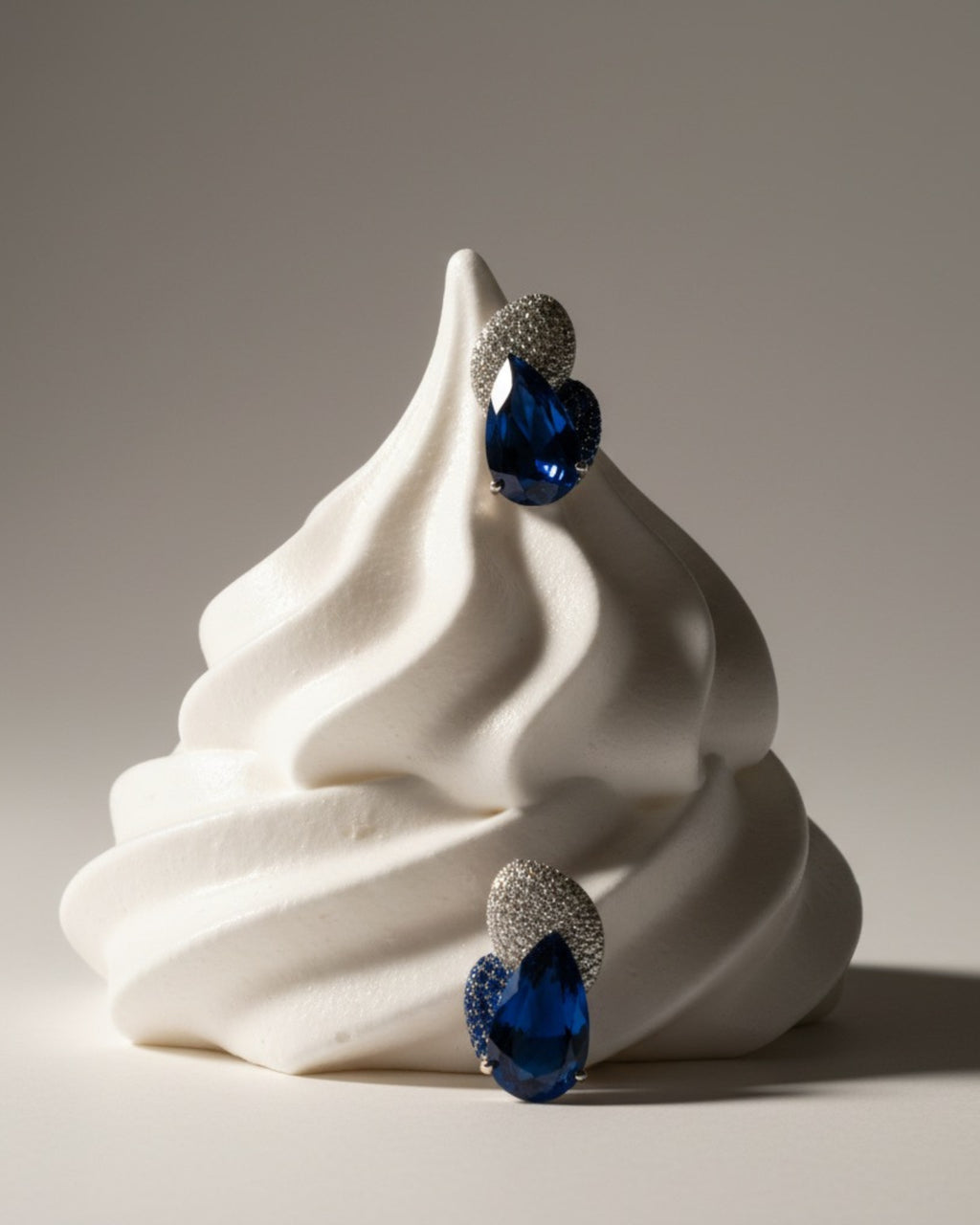 Pendientes con piedra azul en talla gota rodeada de pequeños destellos brillantes en un diseño refinado.