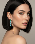 Pendientes largos Indian en rodio con piedras turquesa y esmeralda en talla gota. Su diseño estiliza el rostro y aporta un toque glamuroso.