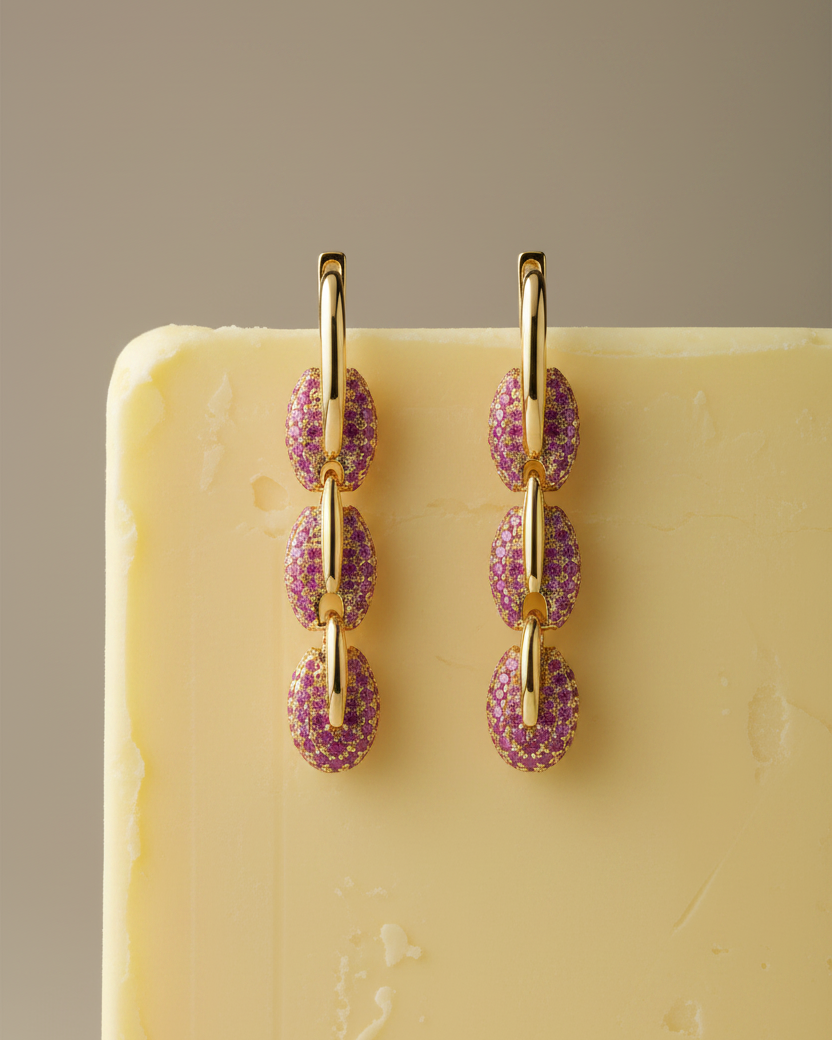 Pendientes dorados de estilo industrial con piedras rosas y brillo sofisticado.