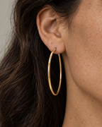 Macro lateral del pendiente LoopPendientes LOOP de diseño circular con acabado amarillo y presencia elegante.