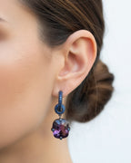 Pendientes Lyss con brillo intenso en rodio negro, decorados con piedras azules y violeta. Diseño sofisticado que aporta profundidad y elegancia.