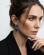 Pendientes Lyss con diseño de lujo en rodio negro, protagonizados por una piedra violeta central y detalles en zafiro azul. Perfectos para eventos y noches especiales.
