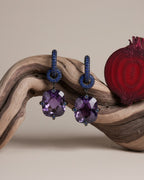 Pendientes largos Lyss en rodio negro con piedra violeta central de gran tamaño y detalles en zafiro azul. Una pieza sofisticada ideal para looks de noche.