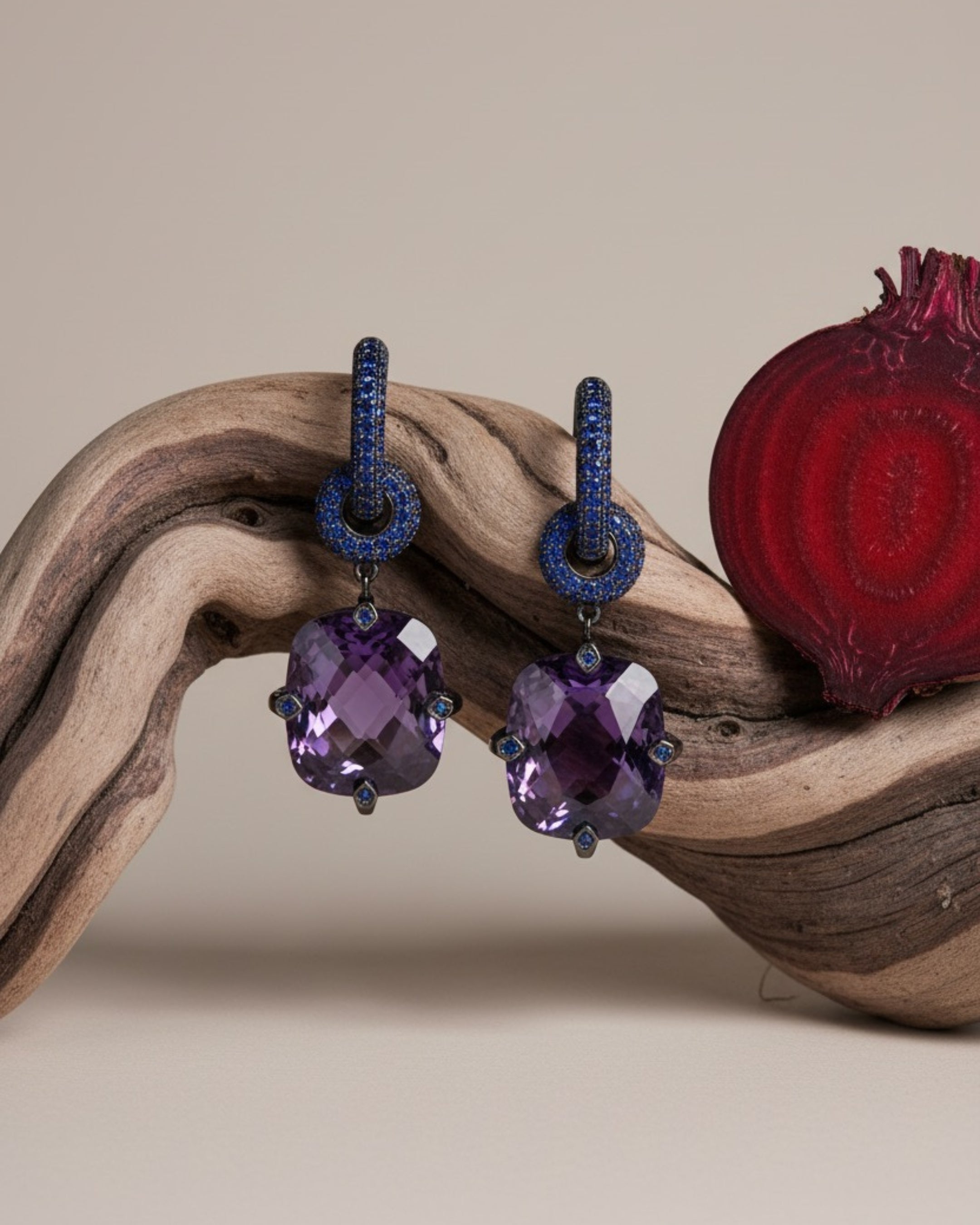 Pendientes largos Lyss en rodio negro con piedra violeta central de gran tamaño y detalles en zafiro azul. Una pieza sofisticada ideal para looks de noche.