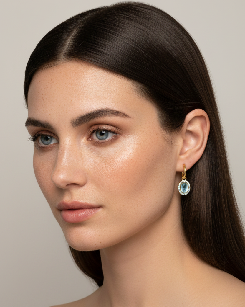 Pendientes en oro amarillo con piedra azul aguamarina y diseño sofisticado y femenino.