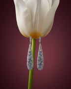 Pendientes Pacific en rodio con piedra azul aguamarina y circonitas en talla circular. Diseño limpio y sofisticado ideal para looks elegantes.