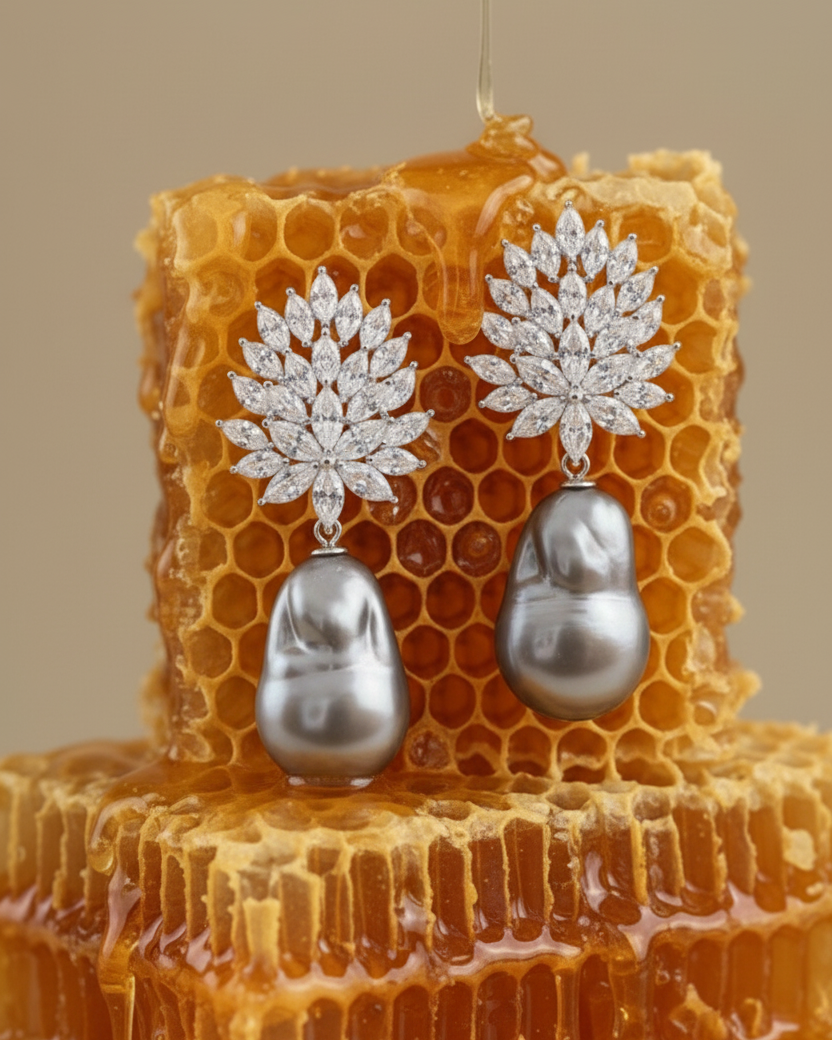 Pendientes sofisticados con gran perla barroca gris y detalles de piedras blancas.