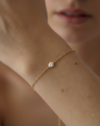 Pulsera minimalista con baño en oro amarillo de 18 kt y piedra central que aporta brillo sutil.