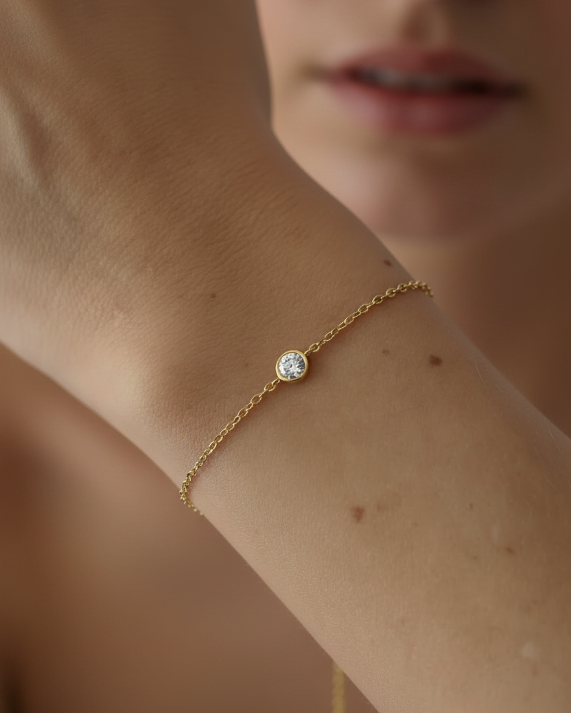 Pulsera minimalista con baño en oro amarillo de 18 kt y piedra central que aporta brillo sutil.