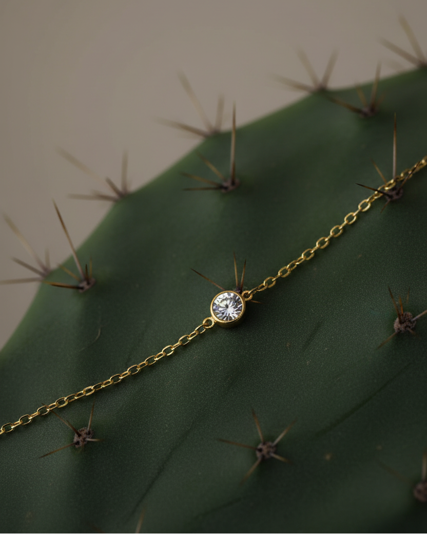 Pulsera delicada con piedra blanca central y acabado en oro amarillo, ideal para uso diario.