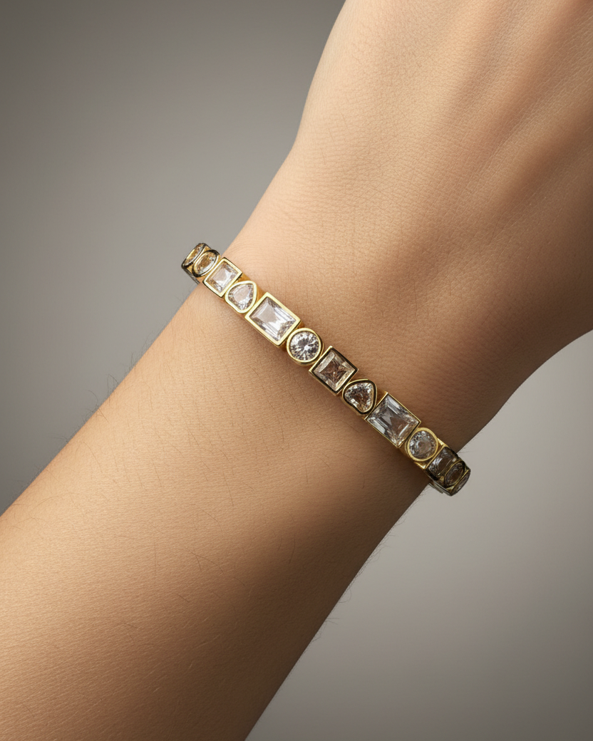 Pulsera KAIR con piedras blancas y chapado en oro amarillo de 18 kt, de estructura rígida y ajustable.