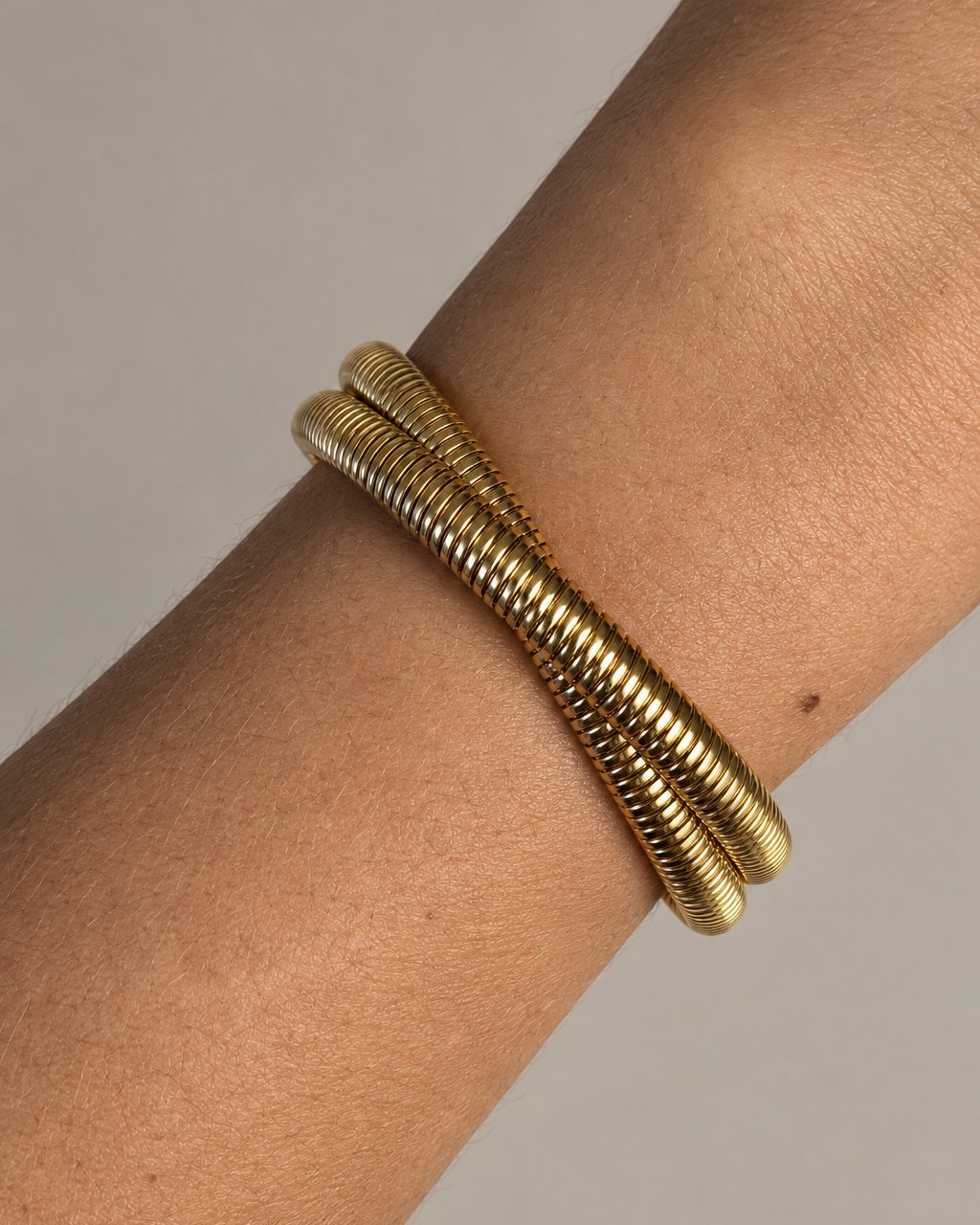 Pulsera rígida VITA abierta con acabado dorado y silueta limpia de inspiración contemporánea.