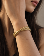 Pulsera VITA dorada de silueta estructurada con diseño abierto y extremos planos.
