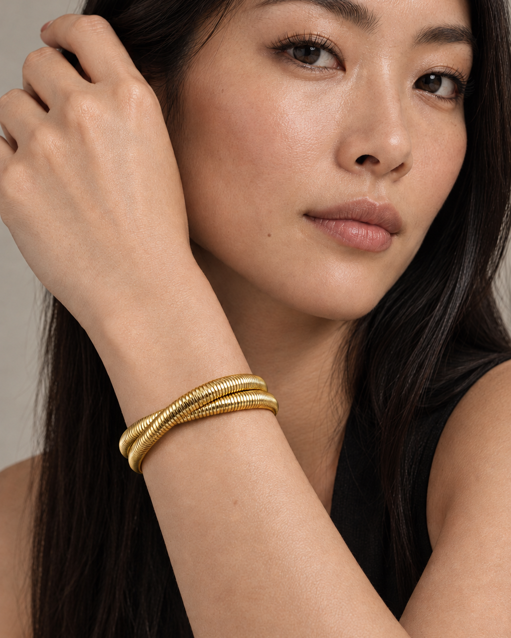 Pulsera VITA rígida dorada de Sibela Studio con diseño abierto y estructura tubular.