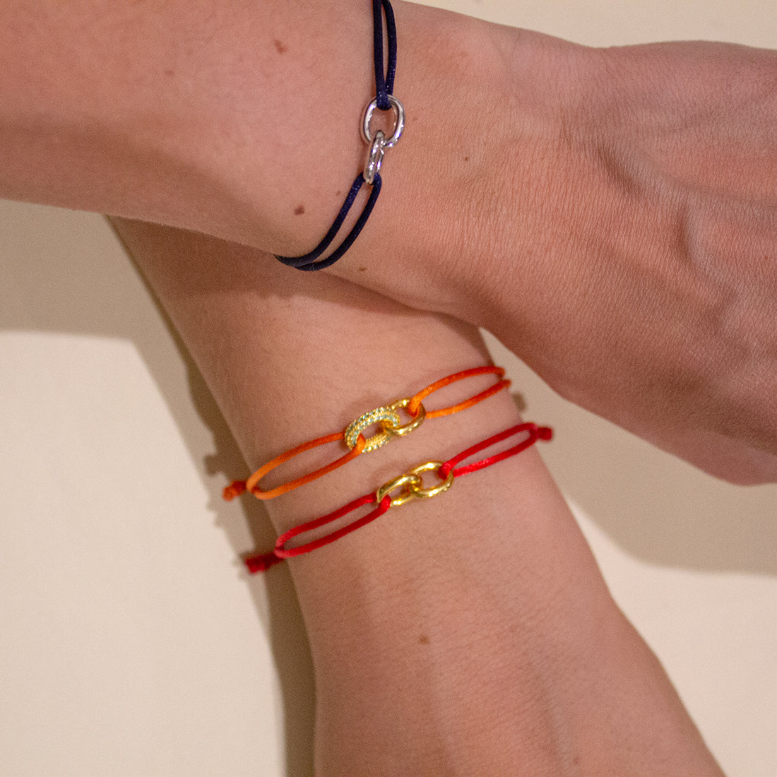 pulsera de cuerda roja con dos eslabones de oro amarillo entrelazados, cuerda roja de 1mm cerrada por ocho nudos 